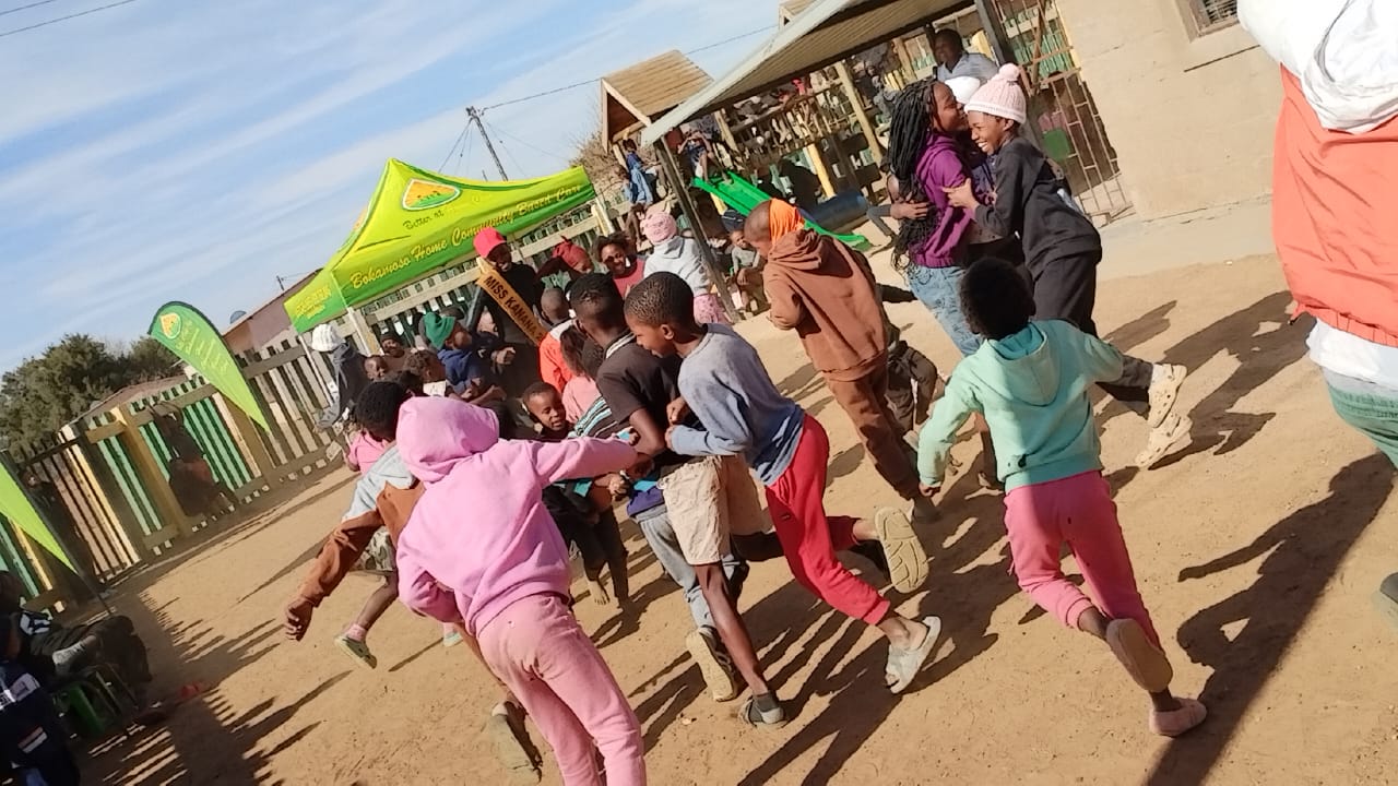 Children playing together outside beneath the Bokamoso canopy