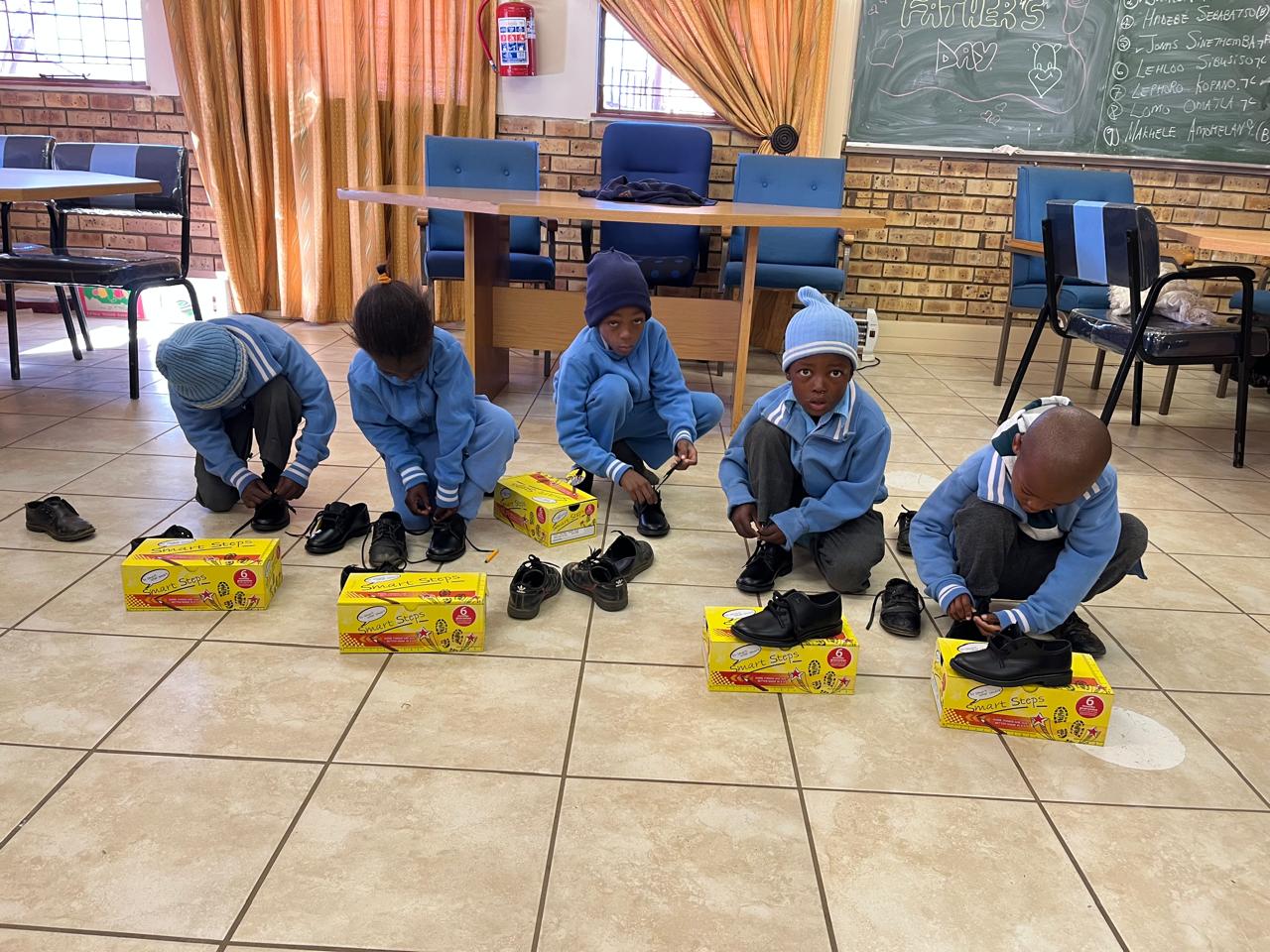Schoolchildren trying on school shoes at the Bokamoso centre
